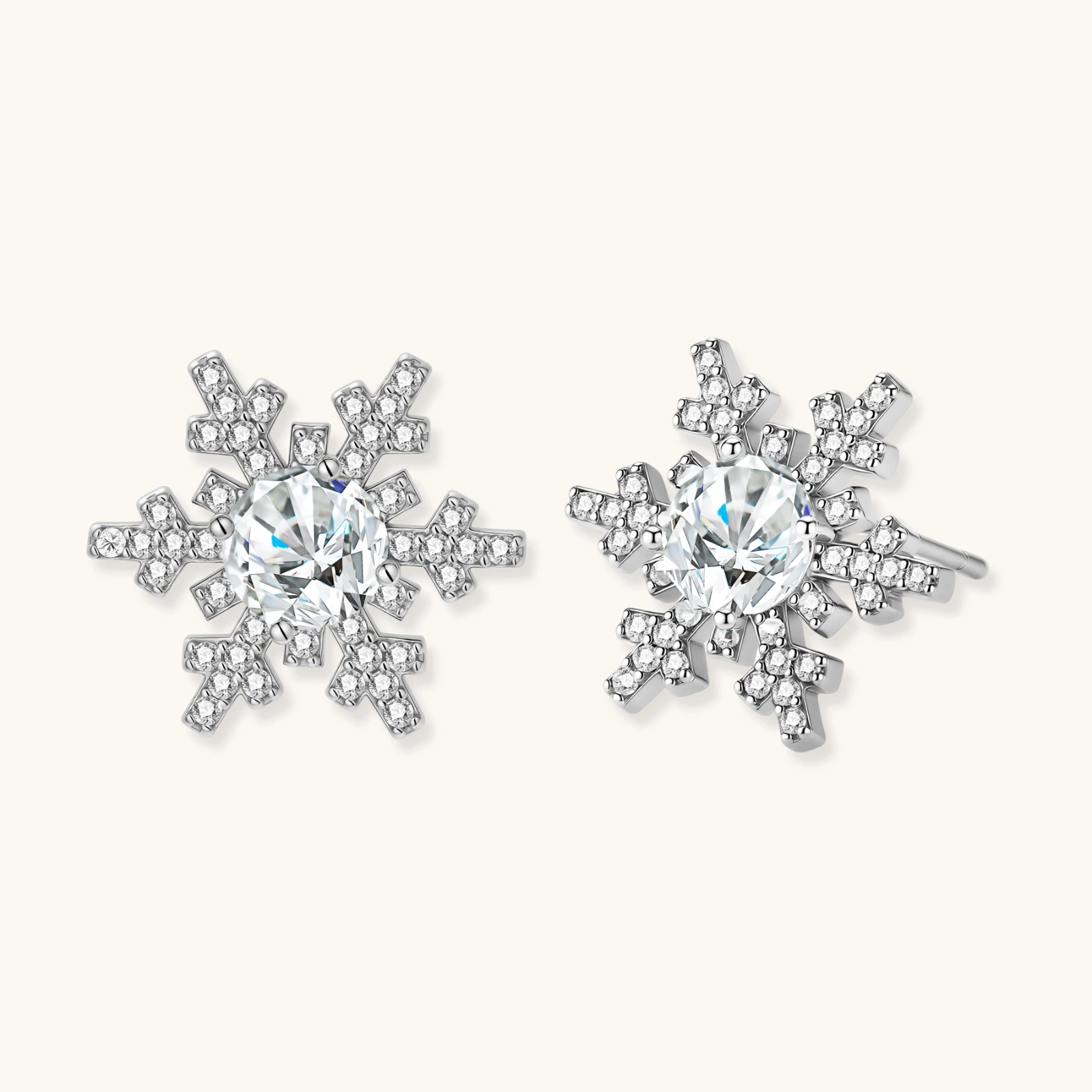Sterling silver snowflake stud earrings with brilliant moissanite centers and intricate geometric patterns on cream background