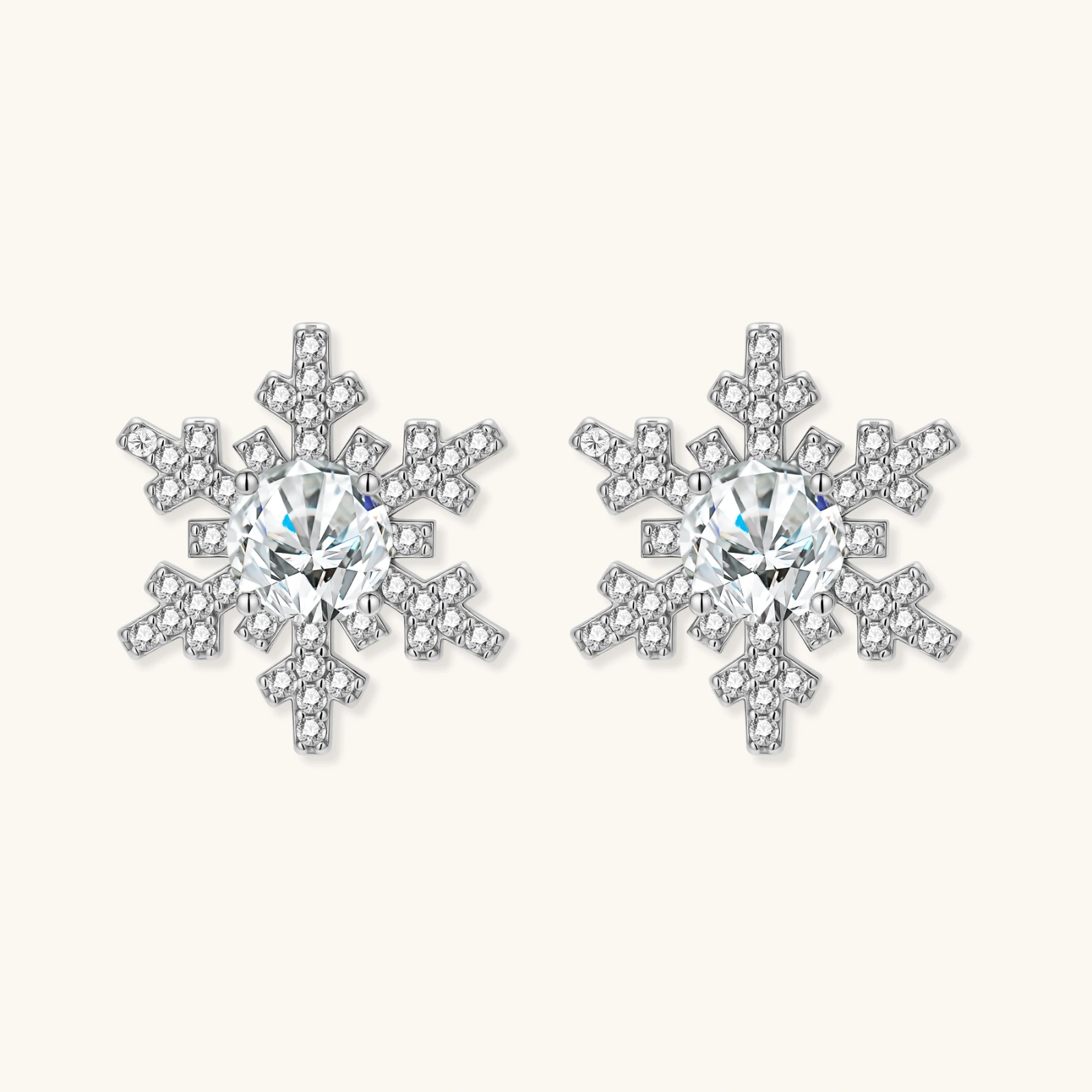 Sterling silver snowflake stud earrings with brilliant moissanite centers and intricate geometric patterns on cream background