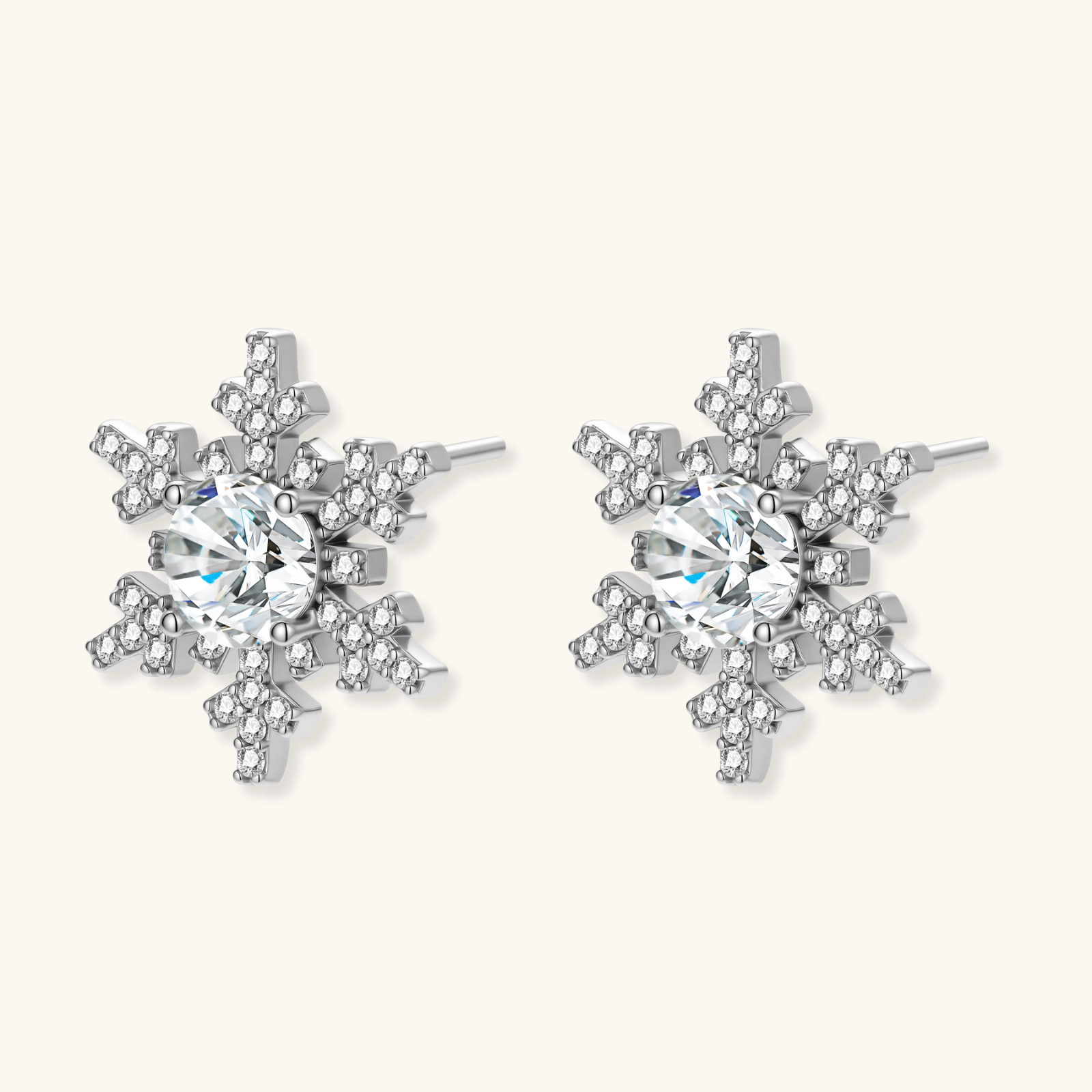 Sterling silver snowflake stud earrings with brilliant moissanite centers and intricate geometric patterns on cream background