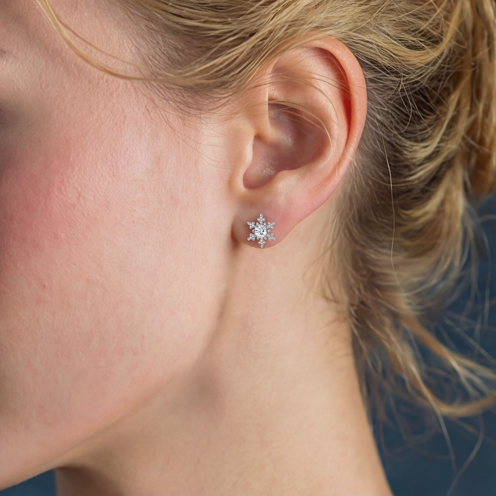 Sterling silver snowflake stud earrings with brilliant moissanite centers and intricate geometric patterns on cream background