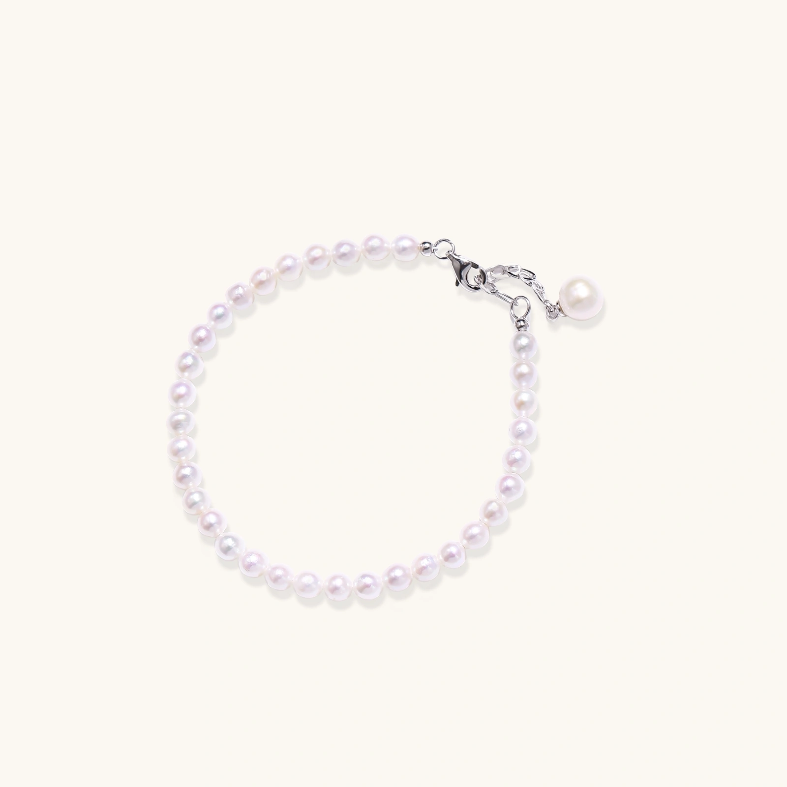 Adjustable bracelet featuring lustrous freshwater pearls with rhodium-plated sterling silver clasp on cream background.