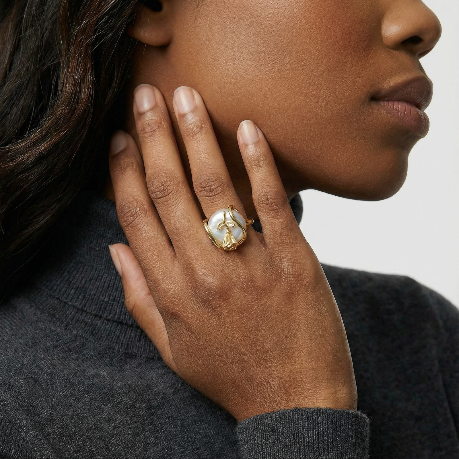 Gold-plated sculptural ring featuring a baroque pearl wrapped in a delicate rose and vine cage design