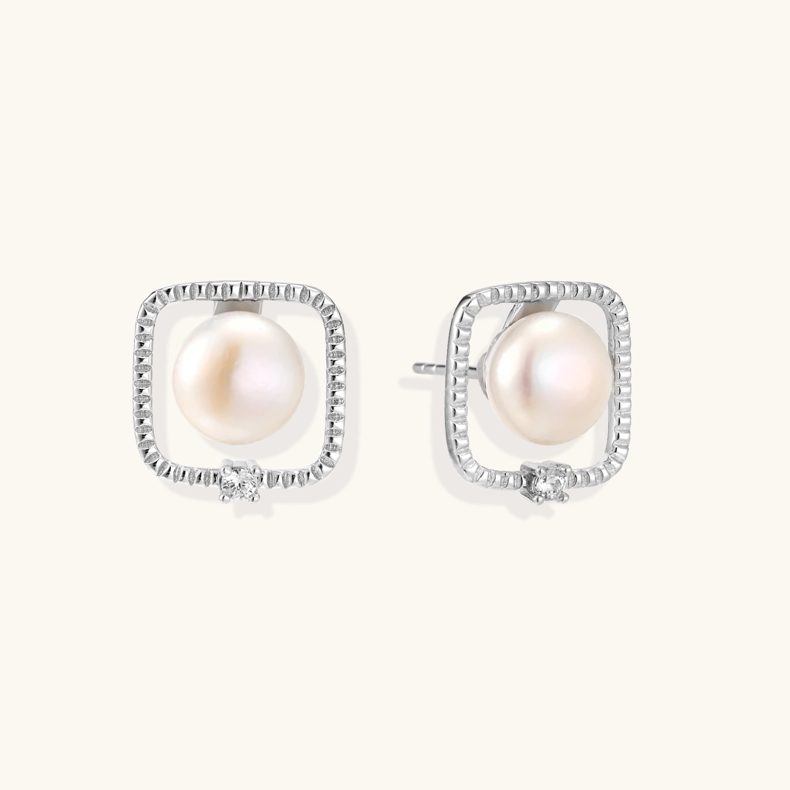 Rhodium-plated silver stud earrings with cushion frame, centered freshwater pearl, and tiny crystal accent