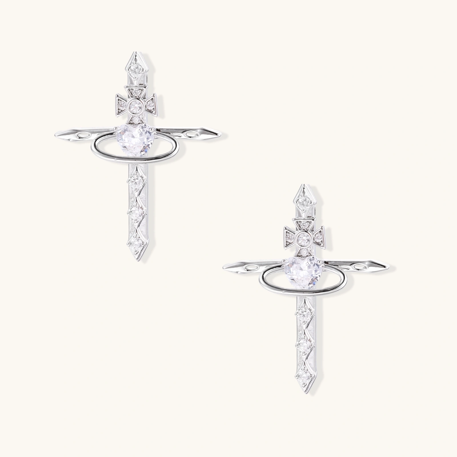 White gold plated cross earrings with orbital ring & zirconia stones on cream background