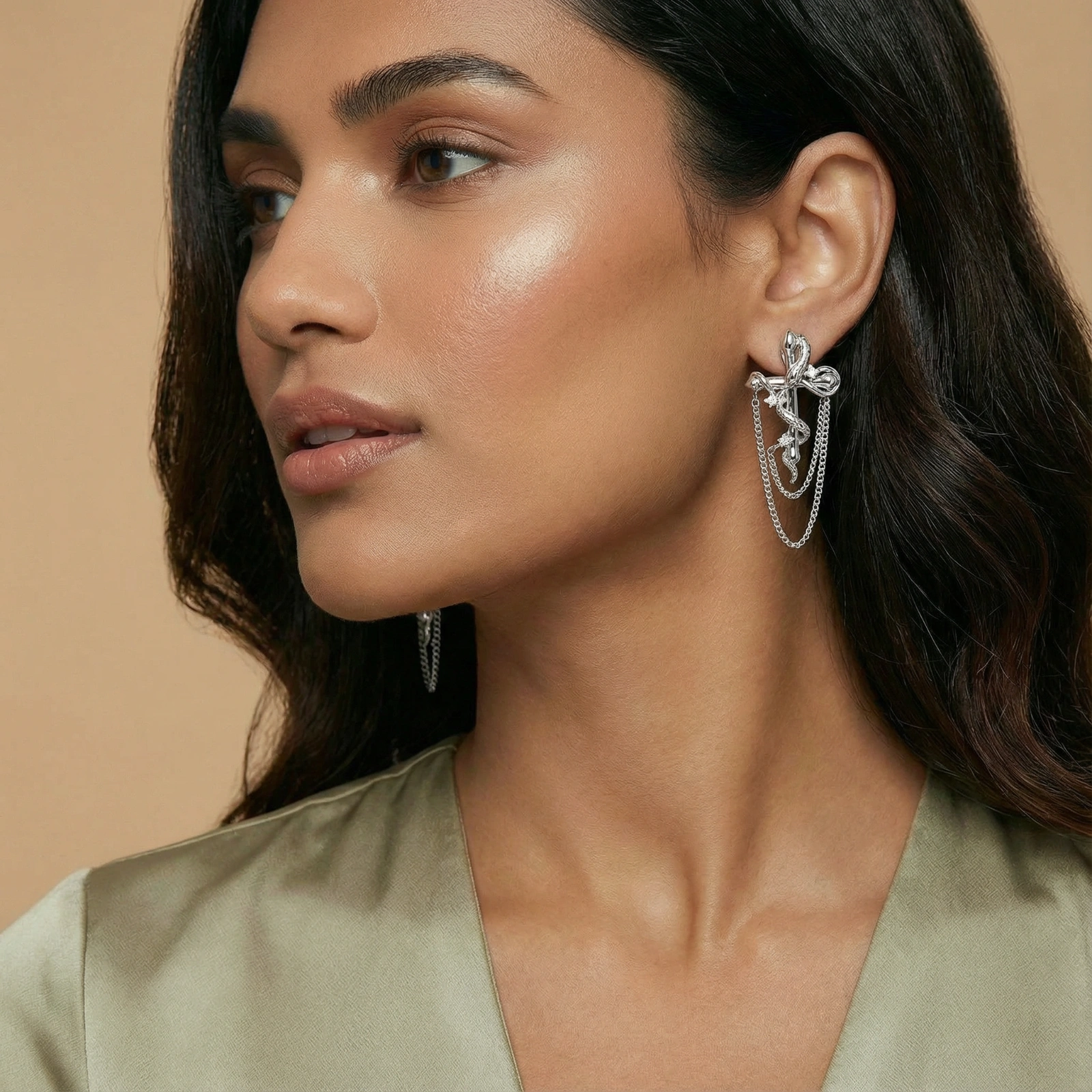 Sculptural white gold bow earrings with cascading chain details on neutral background