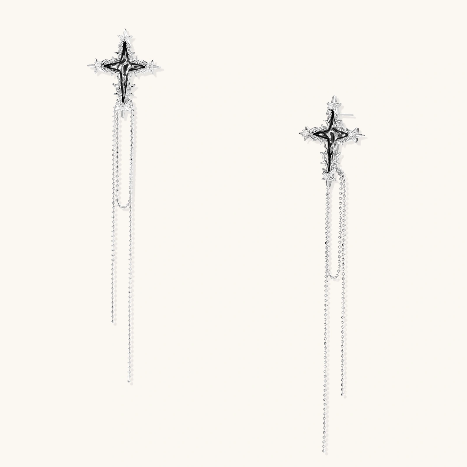 Long silver threader earrings with ornate cross-star design and delicate dual chain tassels on white background