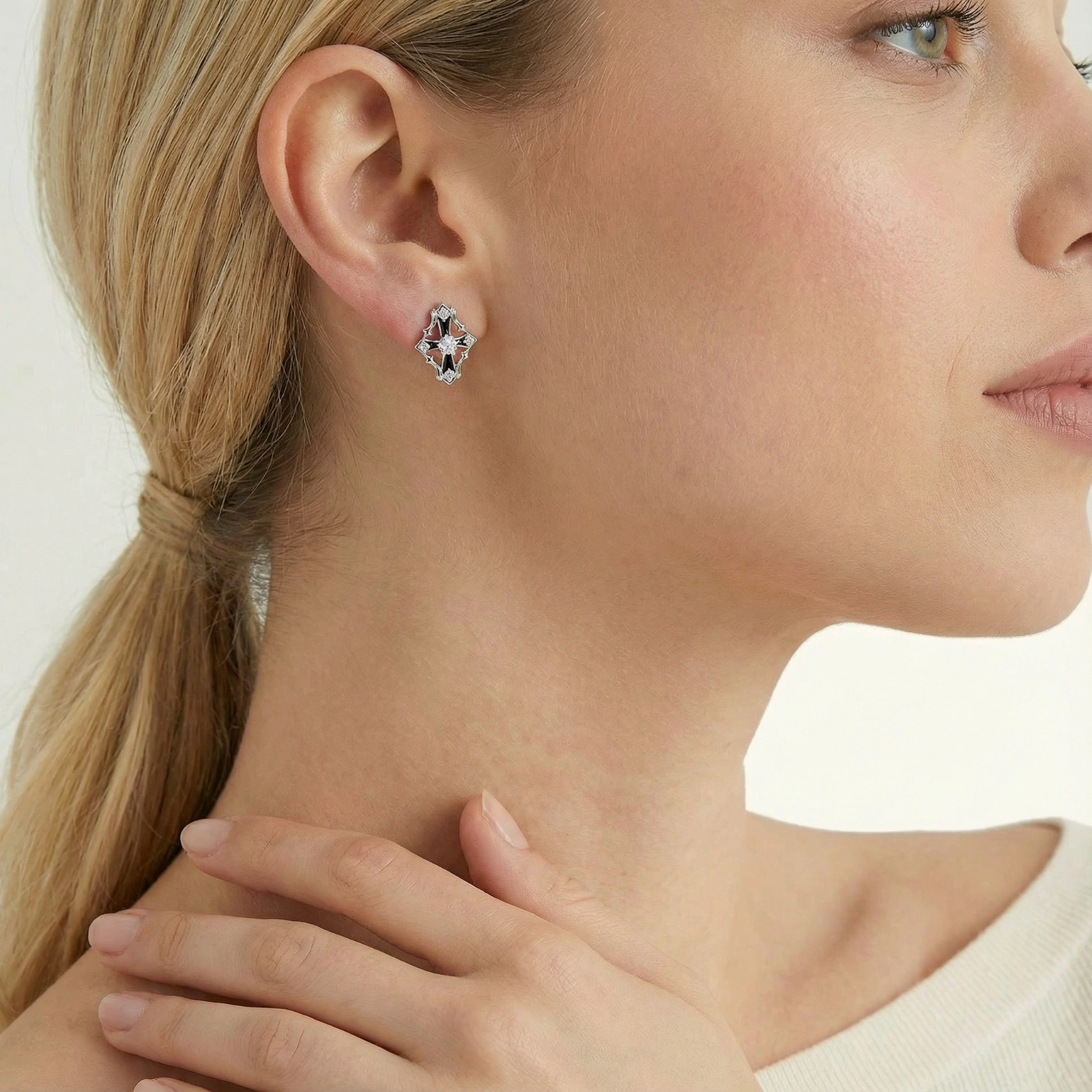 Pair of Art Deco-style stud earrings with star crystals, black enamel accents, and white gold plating on ivory background.