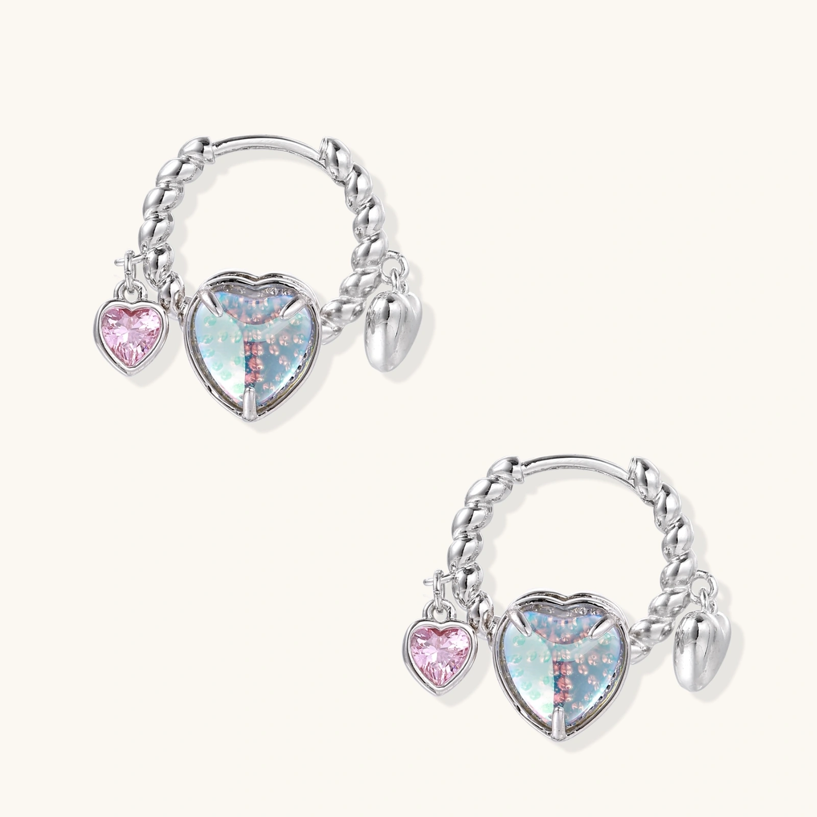 Silver chain hoop earrings with iridescent opal heart charms and pink zirconia accents on white background