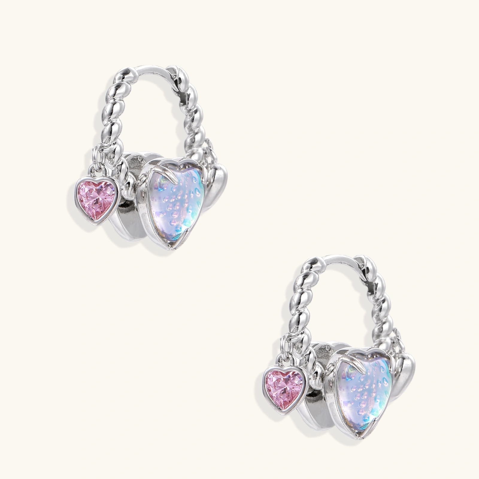 Silver chain hoop earrings with iridescent opal heart charms and pink zirconia accents on white background