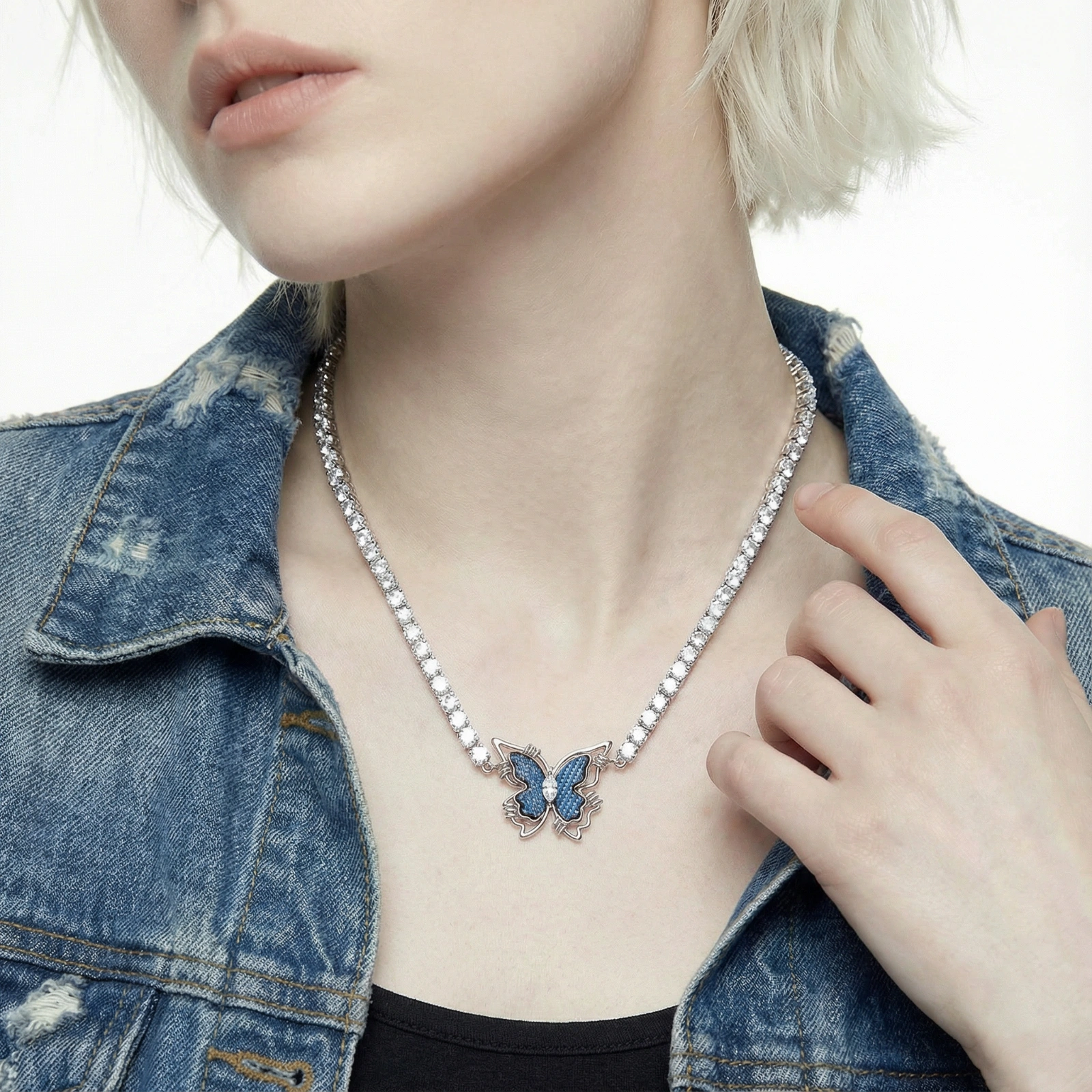 White gold plated tennis necklace with blue denim butterfly pendant and clear zirconia stones on cream background