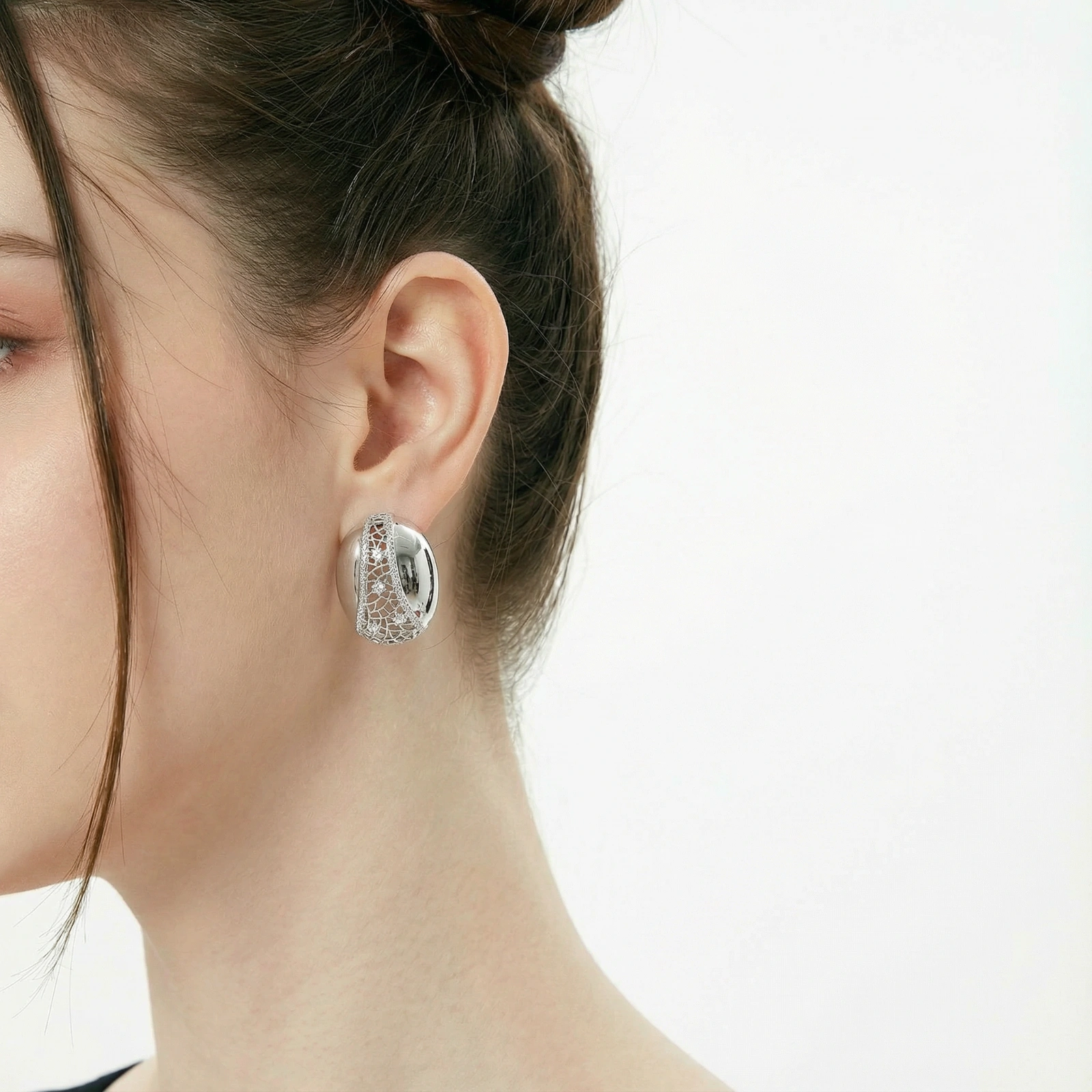 White gold-plated dome hoop earrings with geometric lattice pattern and zirconia stones on cream background