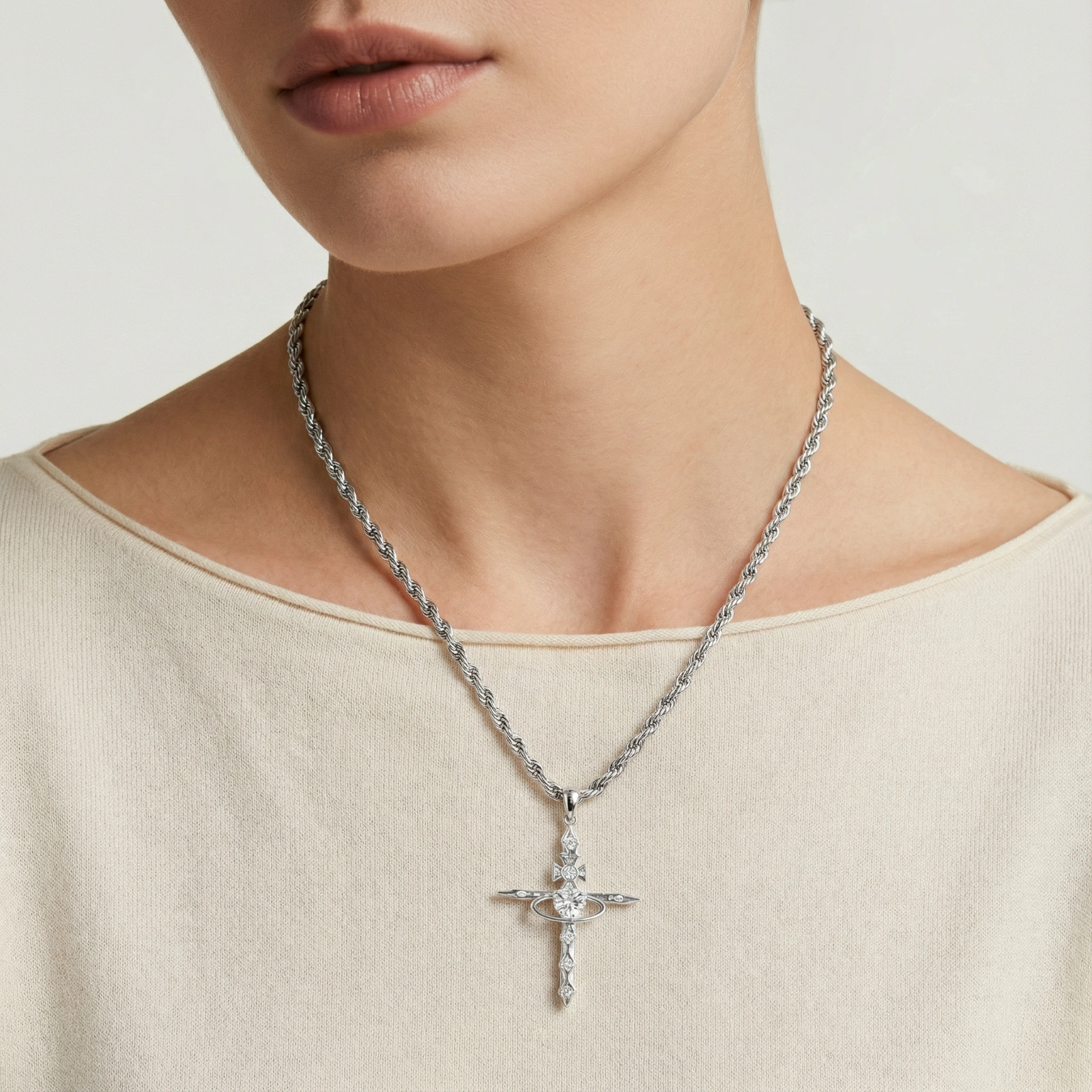 Silver-tone necklace with dimensional orb pendant, cross crown detail, and zirconia stones on twisted rope chain
