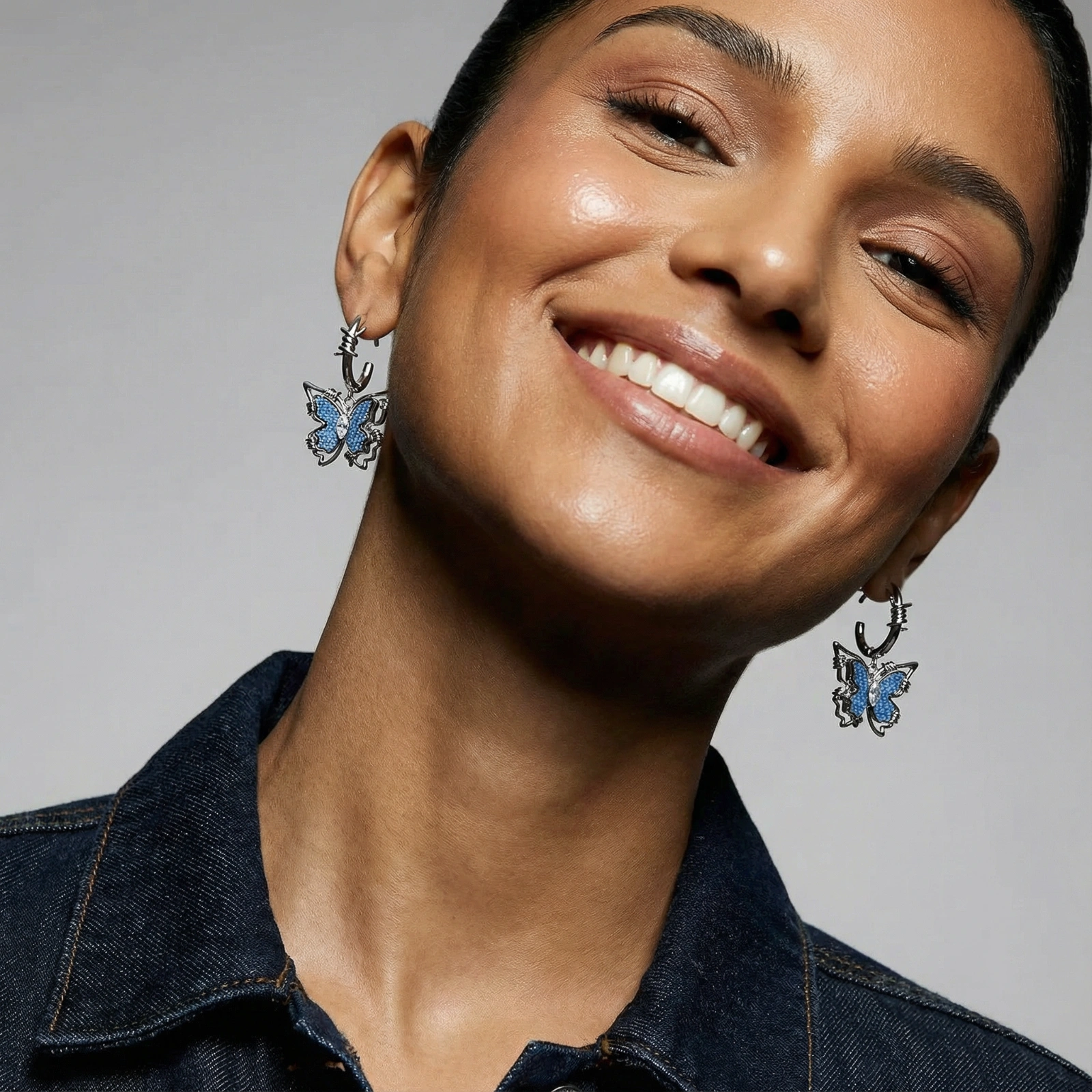 Silver hoop earrings with blue denim butterfly charms outlined in barbed wire design and central zirconia stone