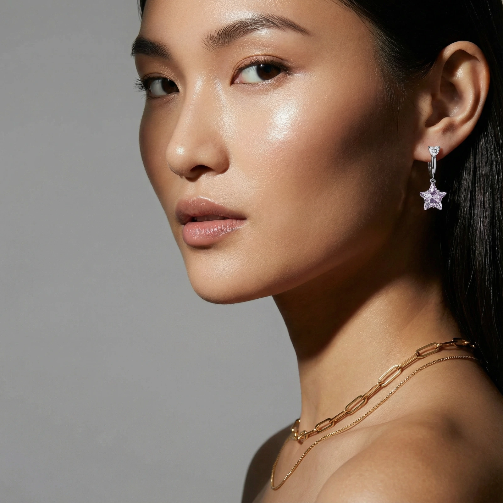 White gold plated huggie earrings with clear CZ accents and dangling lavender star-shaped crystals on cream background