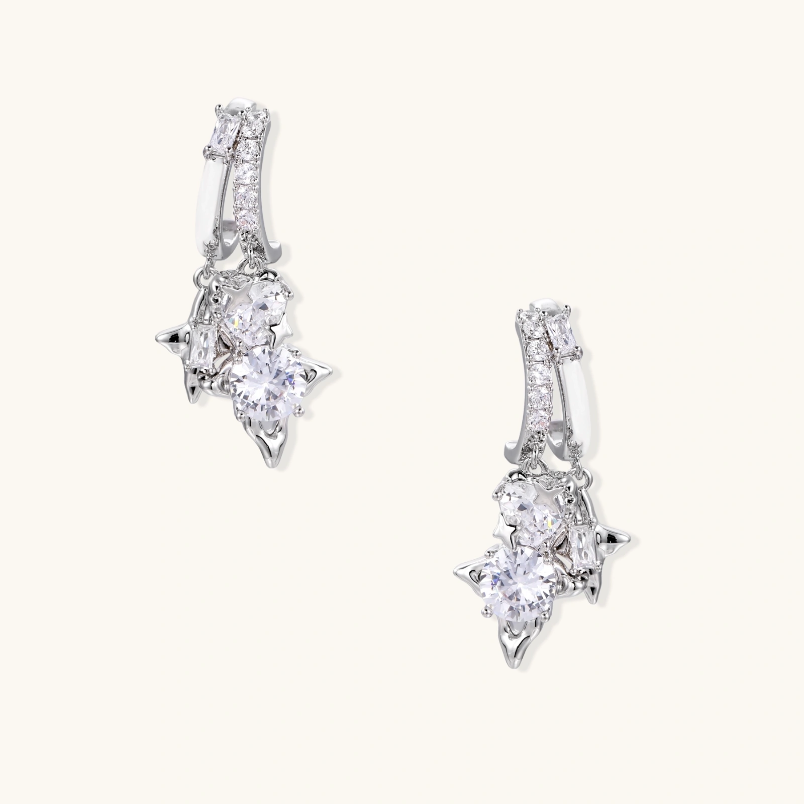 White gold-plated huggie earrings with geometric emerald-cut zirconia clusters in starburst formation on beige background