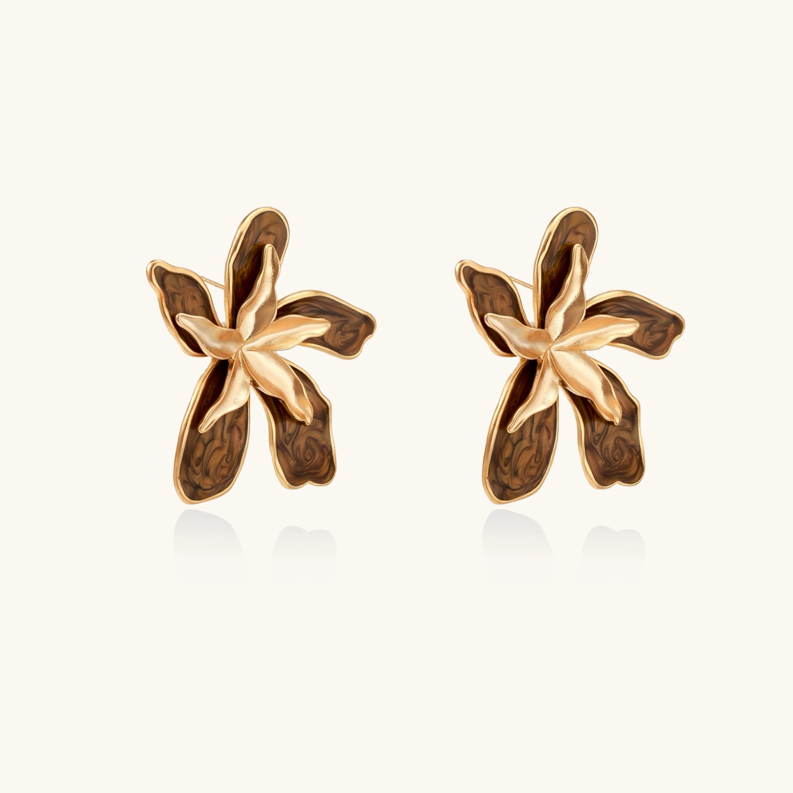 Gold-plated brass flower earrings with brown tortoiseshell enamel petals on cream background