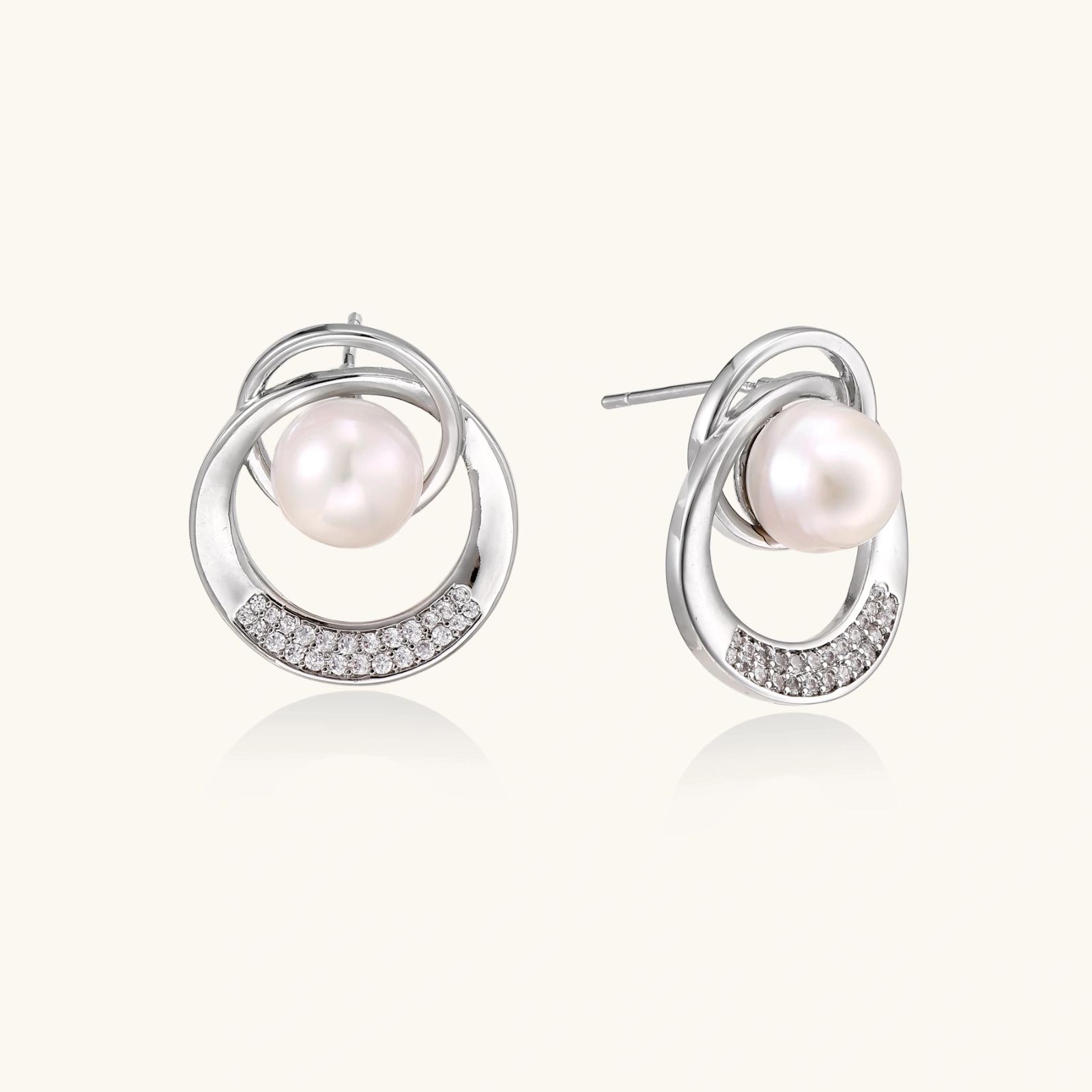 White gold-plated brass earrings with circular design, freshwater pearl center, and diamond accents
