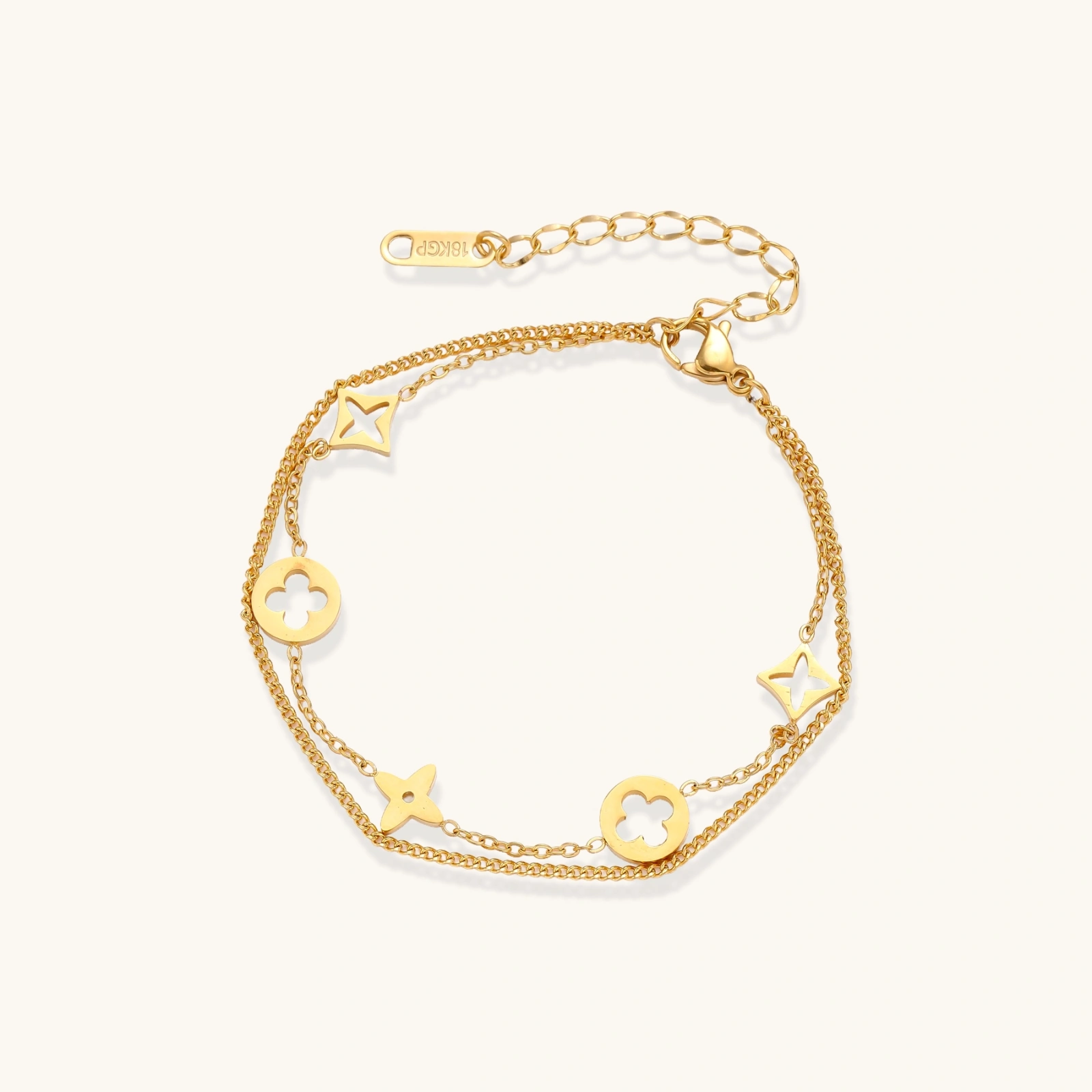 Double-layer gold-plated bracelet with quatrefoil and star charms on cream background, 18K gold finish.