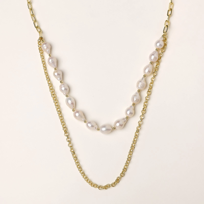 Layered gold chain necklace with organic baroque freshwater pearls and adjustable length on cream background