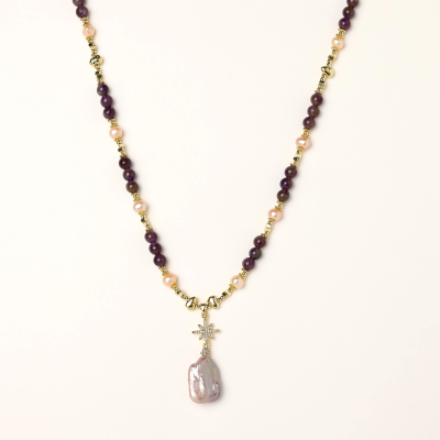 Gold necklace with iridescent baroque pearl pendant, purple amethyst beads, and crystal star charm on cream background
