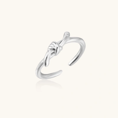 Delicate rhodium-plated silver ring with elegant knot design on cream background, adjustable band style