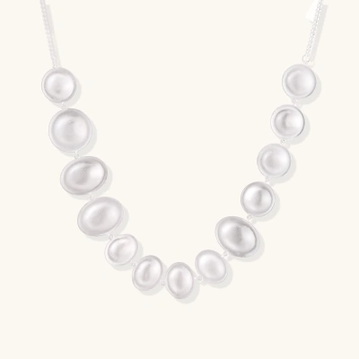 Graduated pearl-finish silver discs forming an organic bubble bib necklace on delicate chain against cream background.