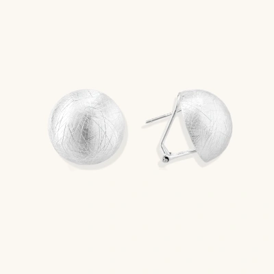 Brushed sterling silver half-dome clip-on earrings with textured surface against cream background