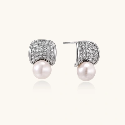 Curved pavé diamond studs in white gold-plated brass cradle lustrous freshwater pearls against cream background