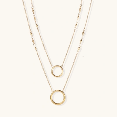 Layered gold necklace set with two open circle pendants and mixed chain styles on beige background