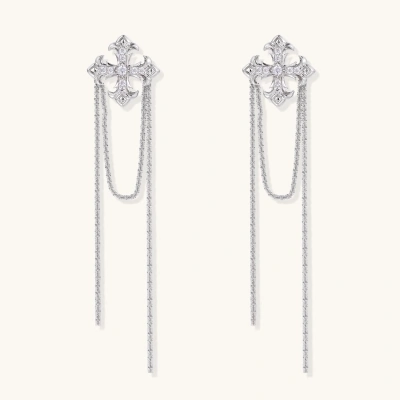 White gold plated baroque cross stud earrings with long cascading zirconia chains on cream background