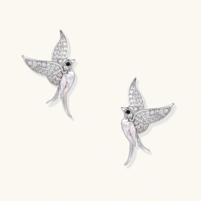 Pair of white gold-plated hummingbird stud earrings with pavé zirconia stones and teardrop crystal bodies on cream background