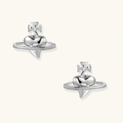Polished white gold-plated Saturn planet stud earrings with orbital rings and crystal-centered cross on beige background