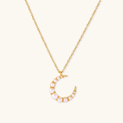 Gold crescent moon pendant with graduated white pearls on delicate chain against cream background