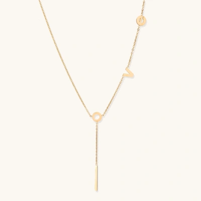 Gold Y-shaped necklace with L-O-V-E letter charms and vertical bar pendant on delicate chain against cream background