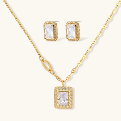 Gold-plated jewelry set with rectangular cubic zirconia stones in pave halo settings on cream background