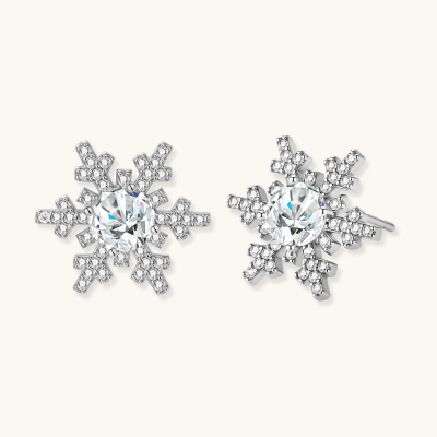 Sterling silver snowflake stud earrings with brilliant moissanite centers and intricate geometric patterns on cream background