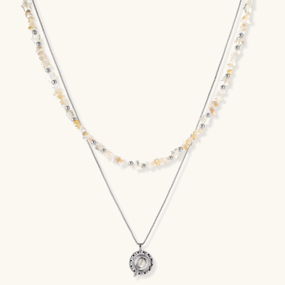 Two-layer necklace with natural stone chips and eco-brass beads, featuring a circular wrapped pendant on cream background.