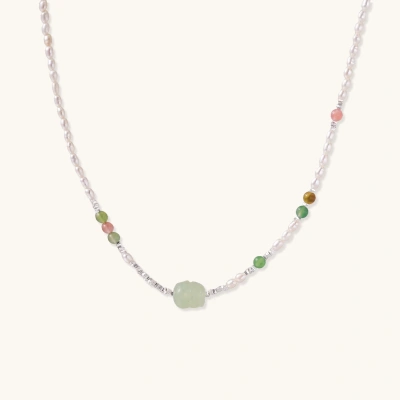 Delicate pearl necklace with pale green serpentine jade centerpiece and colorful agate beads on cream background