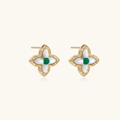 Gold quatrefoil stud earrings with white mother-of-pearl petals and emerald green gemstone center on beige background.