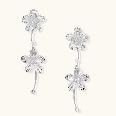 Silver-white asymmetric earrings with textured flower petals and crystal centers on cream background