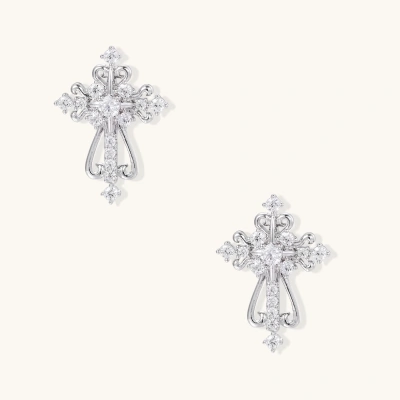 White gold-plated baroque cross studs with zirconia stones and ornate scrollwork on cream background.
