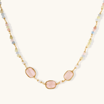 Gold necklace with three rose quartz stones, multicolor pastel beads, and pearl accents on white background.