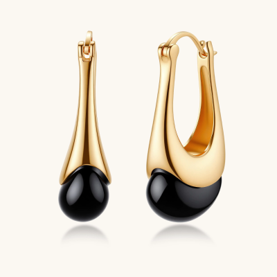 Gold-plated drop earrings featuring black agate stones with hoop closure on white background, showing elegant teardrop design.