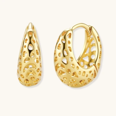Close-up of small gold-plated hoop earrings with intricate honeycomb cutout pattern on cream background.