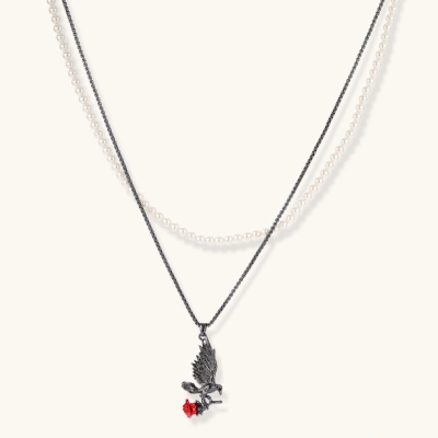 Gothic eagle pendant carrying red rose on black chain layered with white pearls against cream background