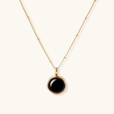Circular black agate pendant on gold-plated sterling silver chain against cream background, showing modern minimalist design.