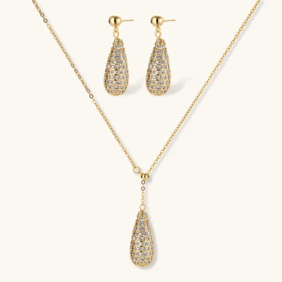 Gold-plated teardrop necklace and earrings covered in AAA cubic zirconia crystals on cream background.