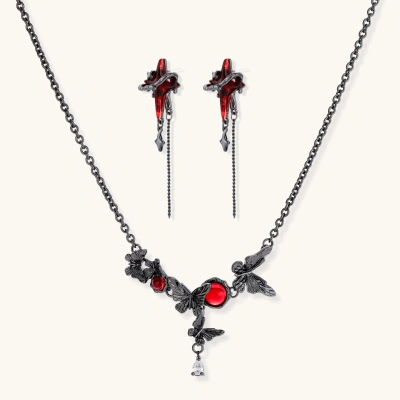 Gothic jewelry set with red resin cross pendants wrapped in dark metal chains on cream background.
