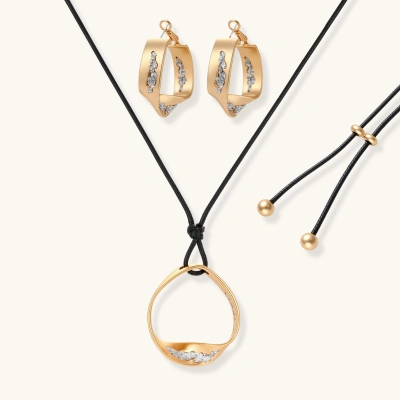 Gold circular pendant necklace with crystals on black cord paired with matching geometric hoop earrings on white background.