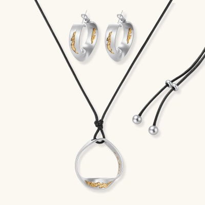 Artistic jewelry set featuring curved silver pendant with gold veining on black cord plus matching asymmetrical hoop earrings